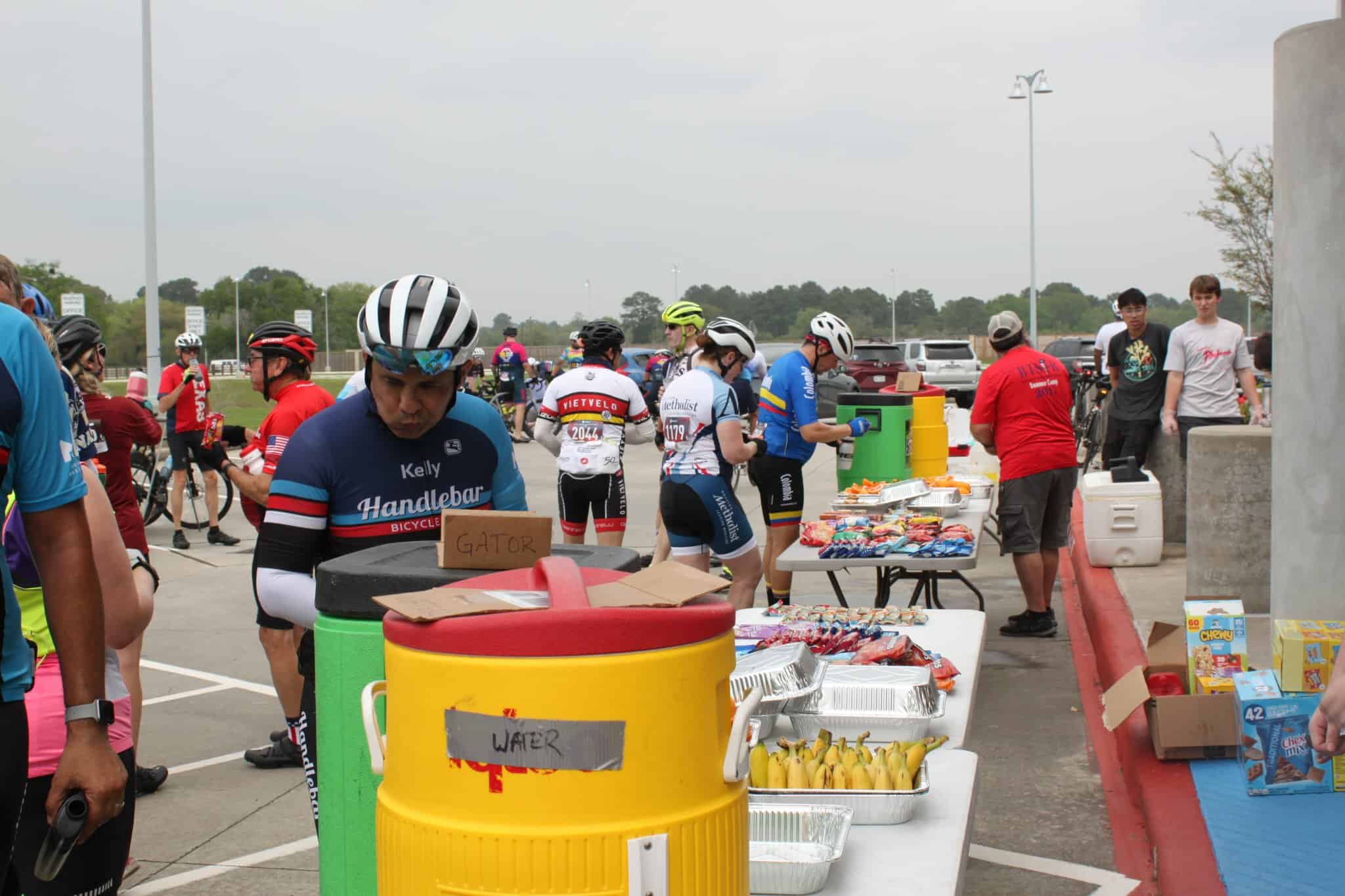 Cyclists enjoying snack break at Bluebonnet Express bike event, with food tables and community atmosphere.