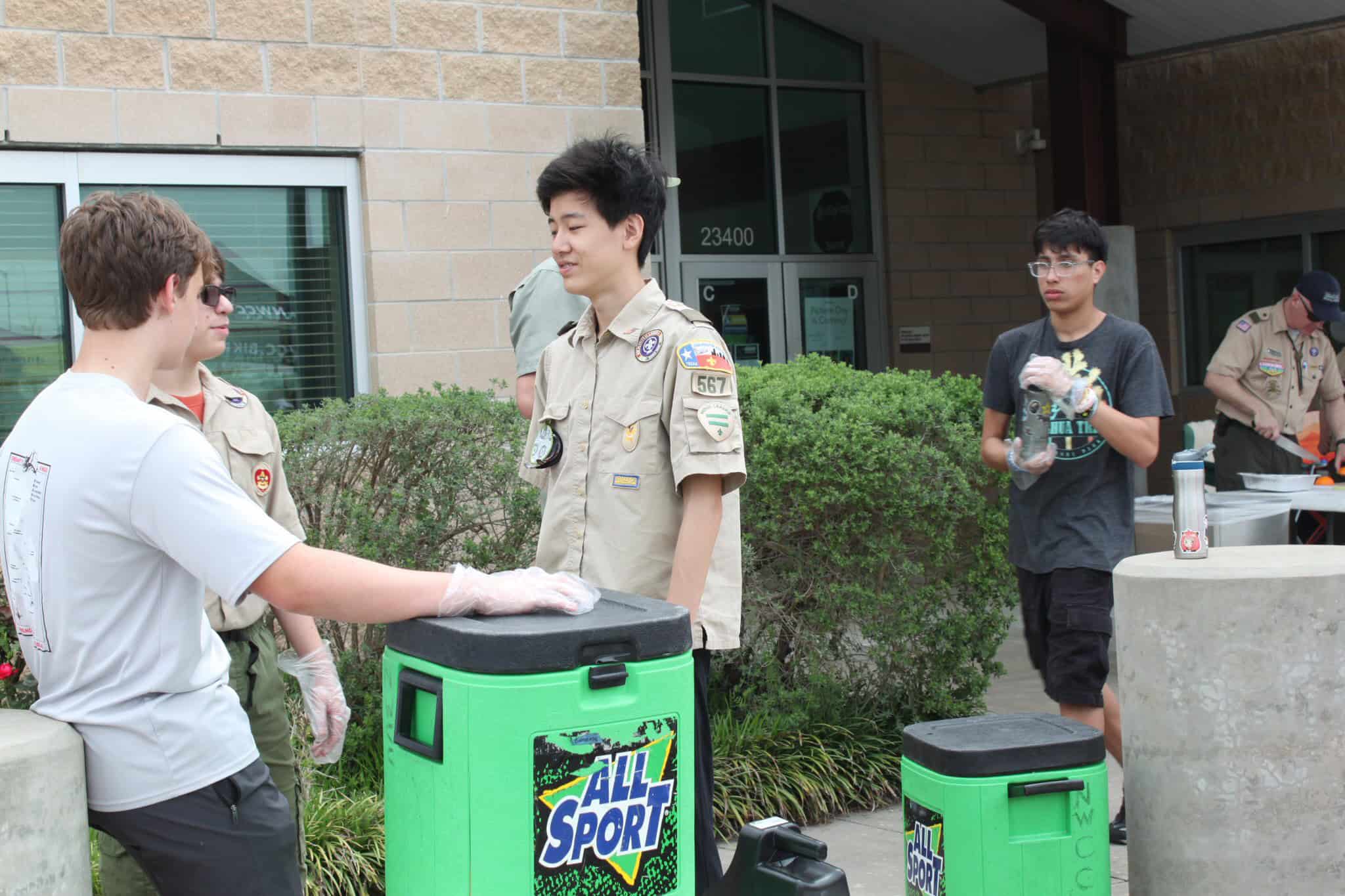 High school scouts volunteering at a community event, serving food and engaging in outdoor activities.