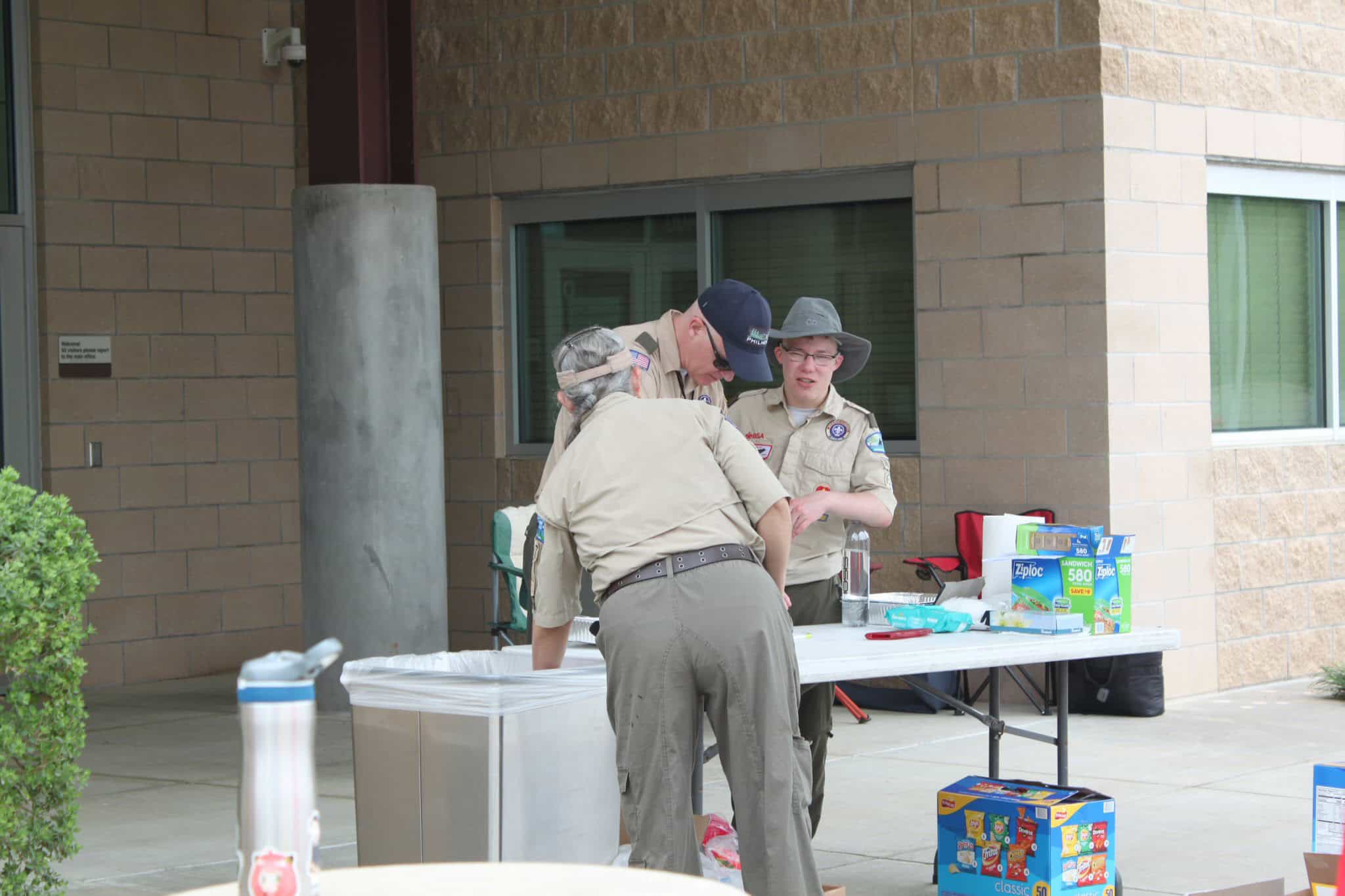 Scouts set up a snack station outdoors, showcasing youth involvement and community activities with camping gear and supplies.