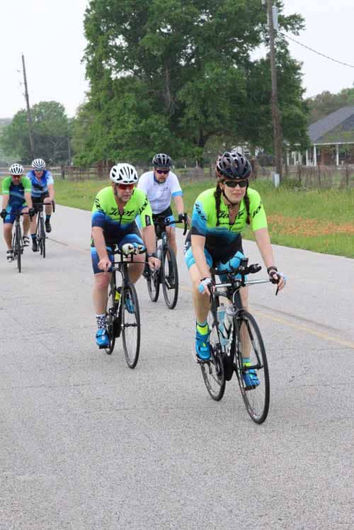 Cyclists riding together on a scenic rural road during the Bluebonnet Express event.