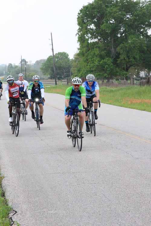 Brightly colored cyclists enjoying a group ride along a scenic rural road during the Bluebonnet Express event.