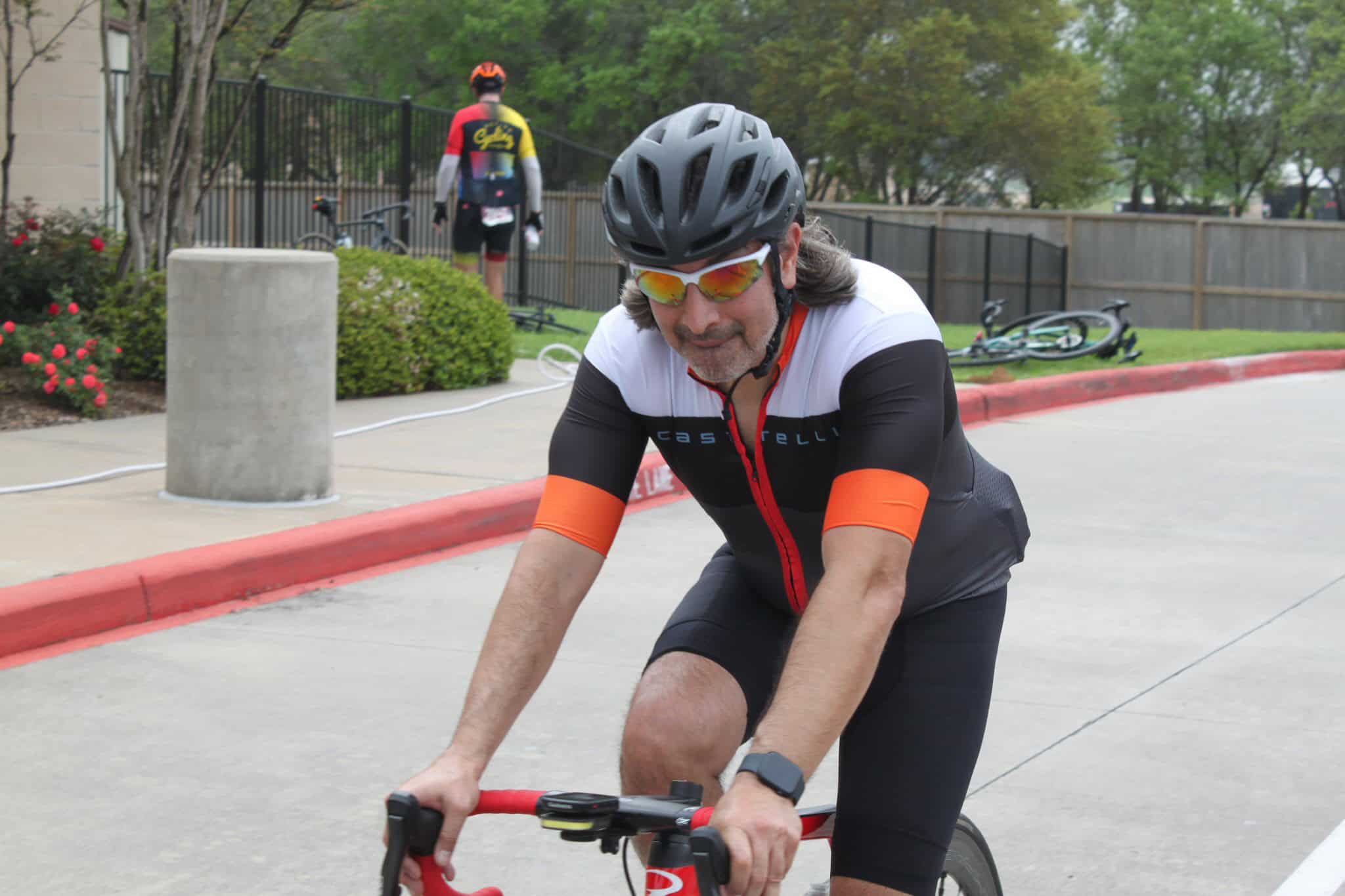 Man riding a bicycle at Bluebonnet Express event in Texas, wearing helmet and cycling gear.