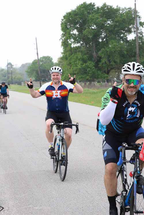 Outdoor group cycling event featuring Bluebonnet Express bike riders, celebrating on scenic rural roads.