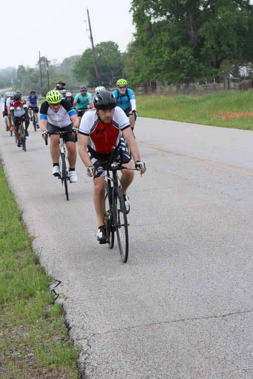 1. Diverse group of cyclists riding on a scenic rural road during Bluebonnet Express event.