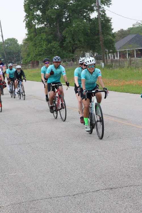 Cycling event with group riders in Bluebonnet Express jerseys, outdoor road bike ride, community cycling activity, Texas biking event.
