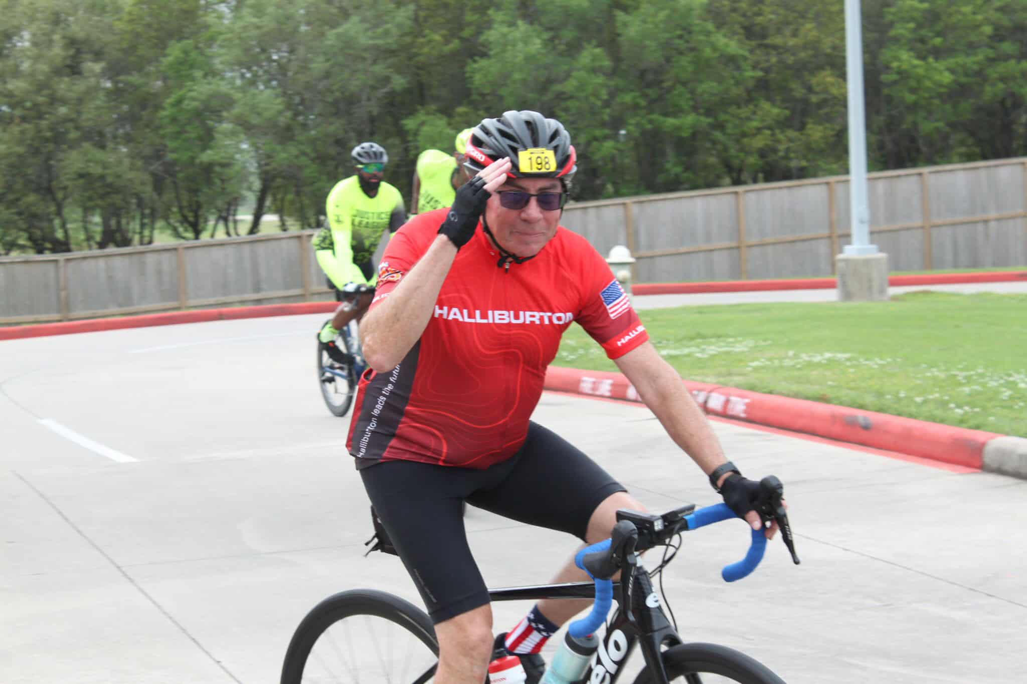 Cheerful cyclist wearing a red Halliburton jersey during a race on a bike path.