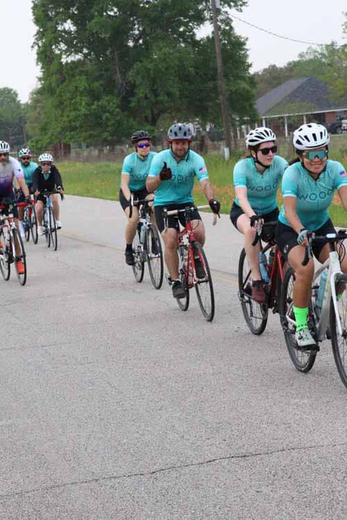 1. Group of cyclists riding on a scenic road during Bluebonnet Express event.