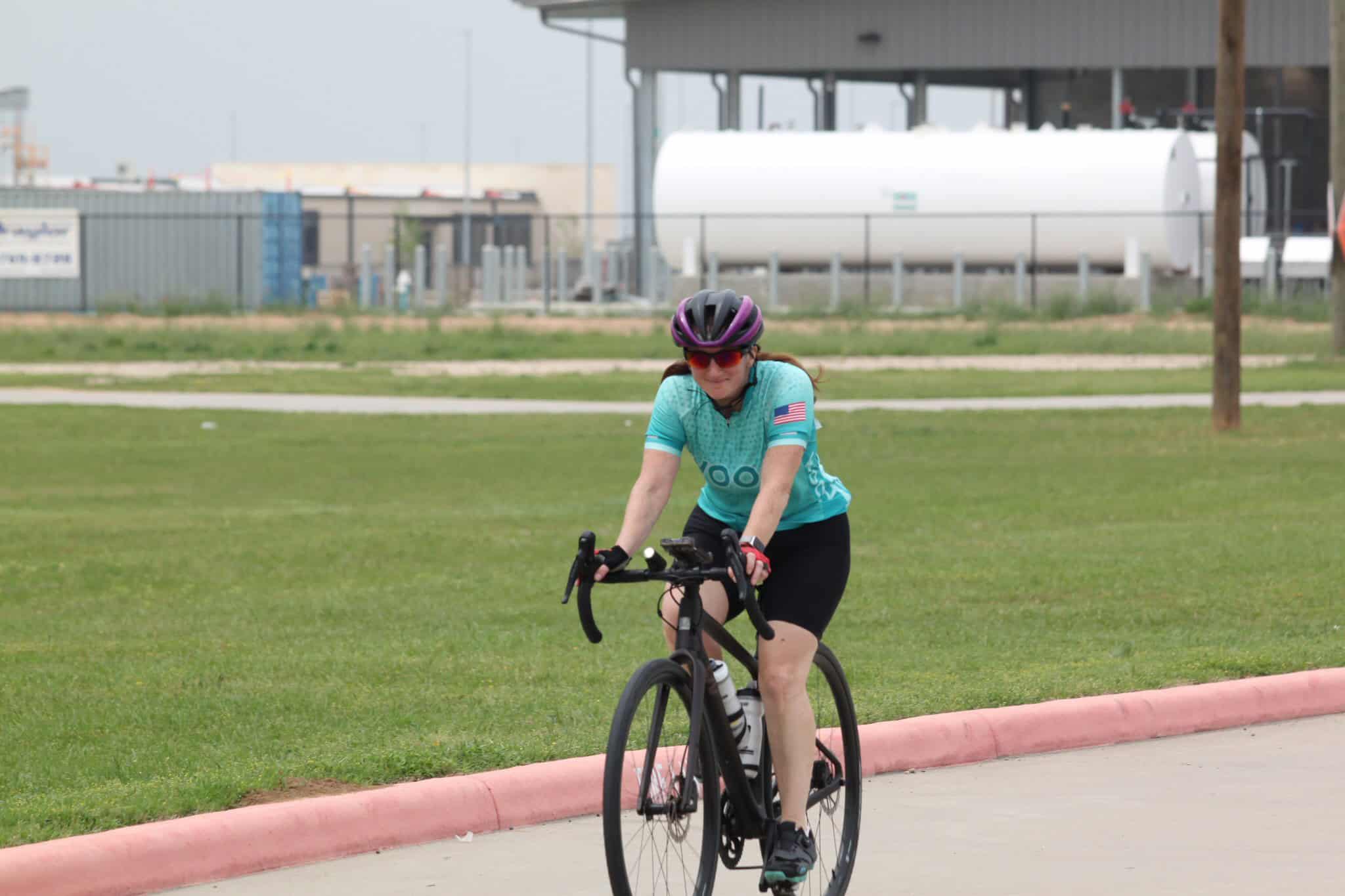 Bike riding on a bicycle path in Texas with Bluebonnet Express branding in the background, emphasizing cycling and local transport.