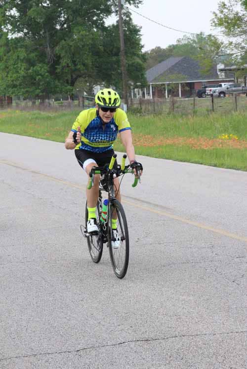Bright yellow and blue cyclist riding on suburban road for Bluebonnet Express event.