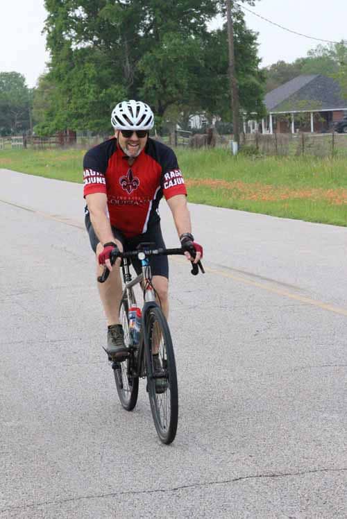 Bright man cycling on road wearing helmet and sporty jersey, outdoor biking for fitness and recreation.