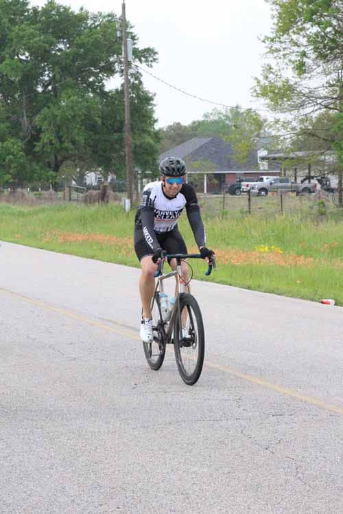High-performance cyclist riding on scenic road, promoting Bluebonnet Express cycling event.