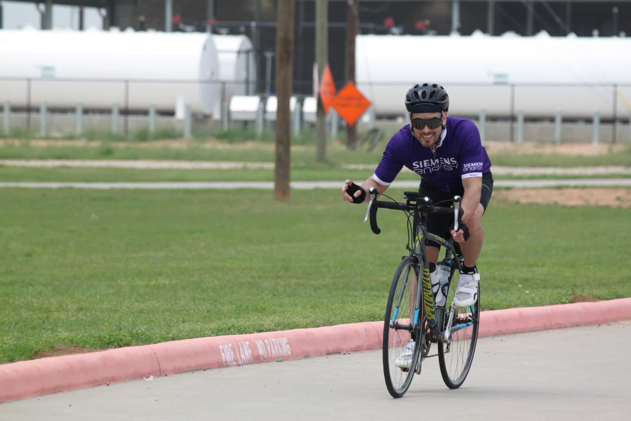 High-quality cycling image, cyclist in purple jersey riding on urban park bike path.
