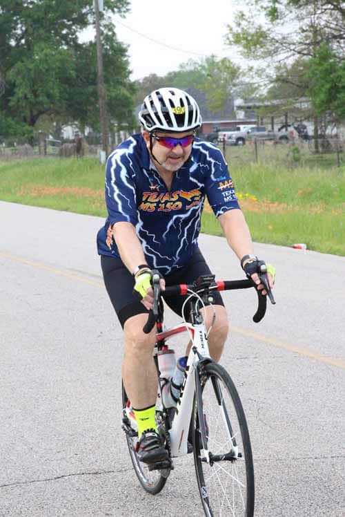 High-performance cyclist riding on a rural road - Bluebonnet Express event focus.
