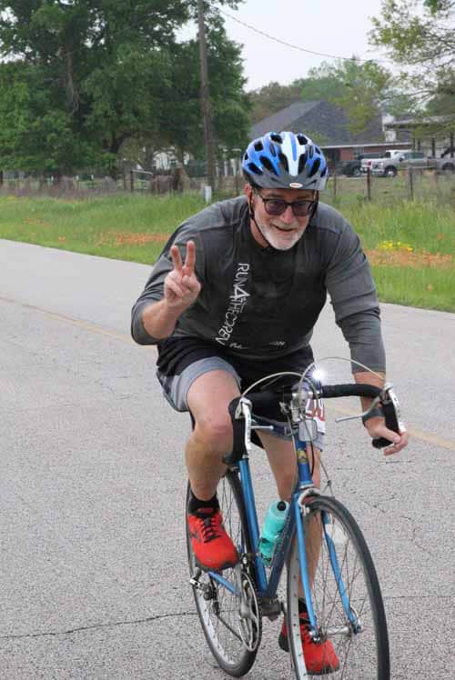 Bluebonnet Express cyclist, joyful ride, peace sign, outdoor biking, scenic route, Texas cycling, fun cycling event.