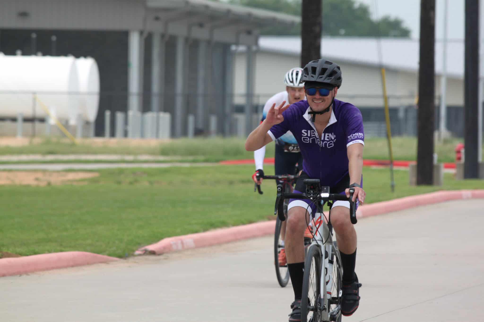 Bright smiling cyclist waving while riding a bike during Bluebonnet Express event, showcasing Austin cycling race.
