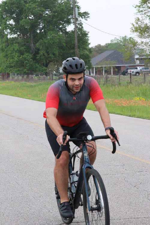Bicycle rider on a scenic road during daytime, promoting Bluebonnet Express biking tours.