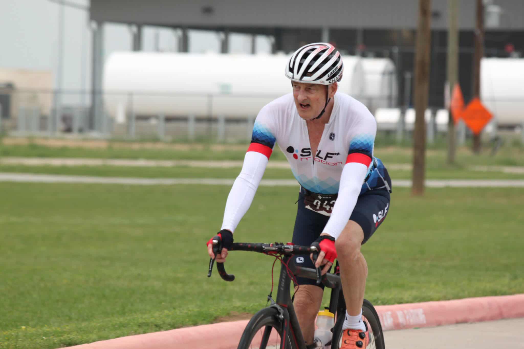1. Man biking outdoors, wearing Bluebonnet Express cycling jersey, competitive rodeo style.