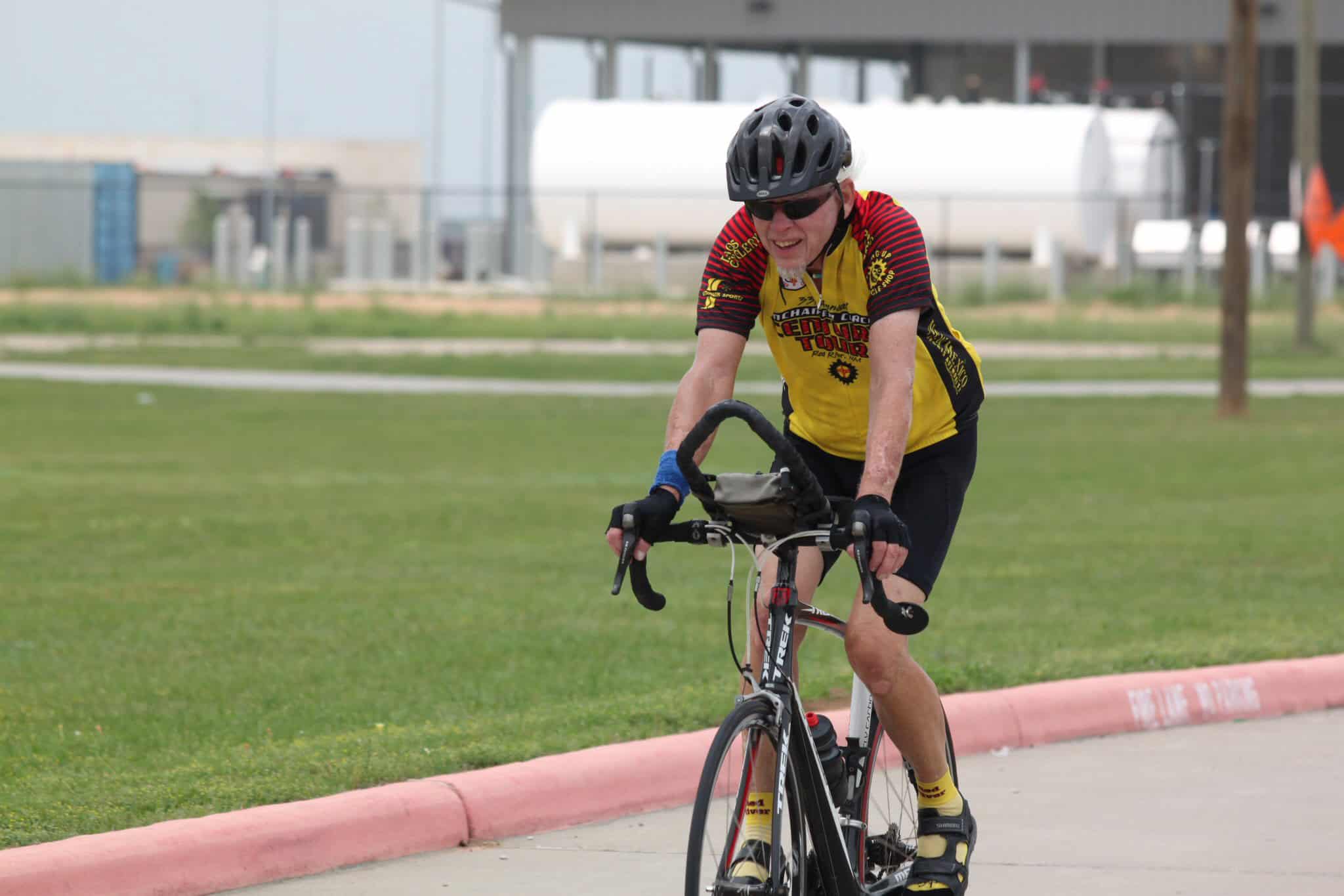 Energetic cyclist riding bicycle in outdoor event, wearing helmet and cycling gear.