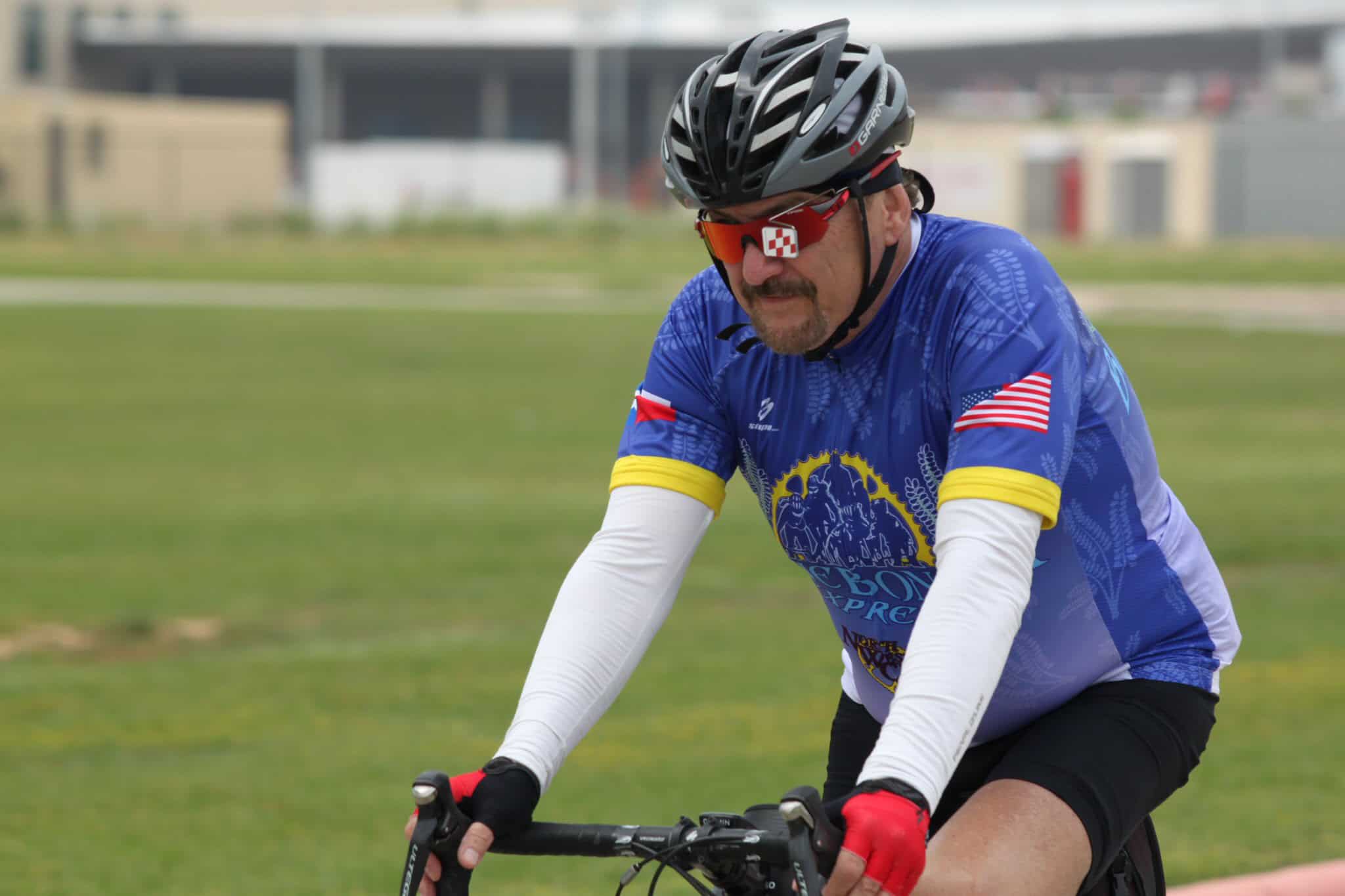 Rider wearing Bluebonnet Express cycling jersey on a mountain bike outdoors.