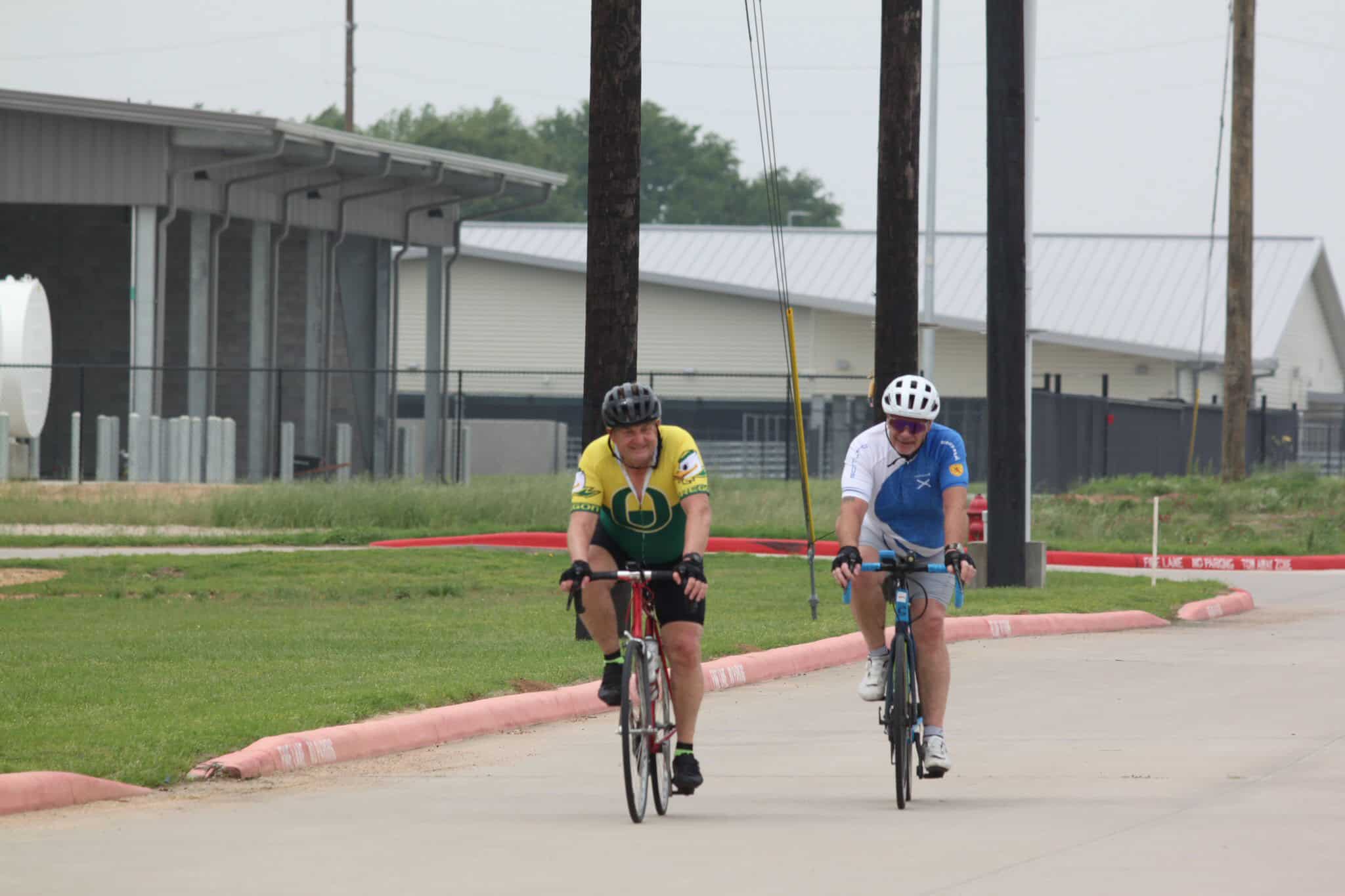 Bike riders cycling on a paved path during a community event or race.