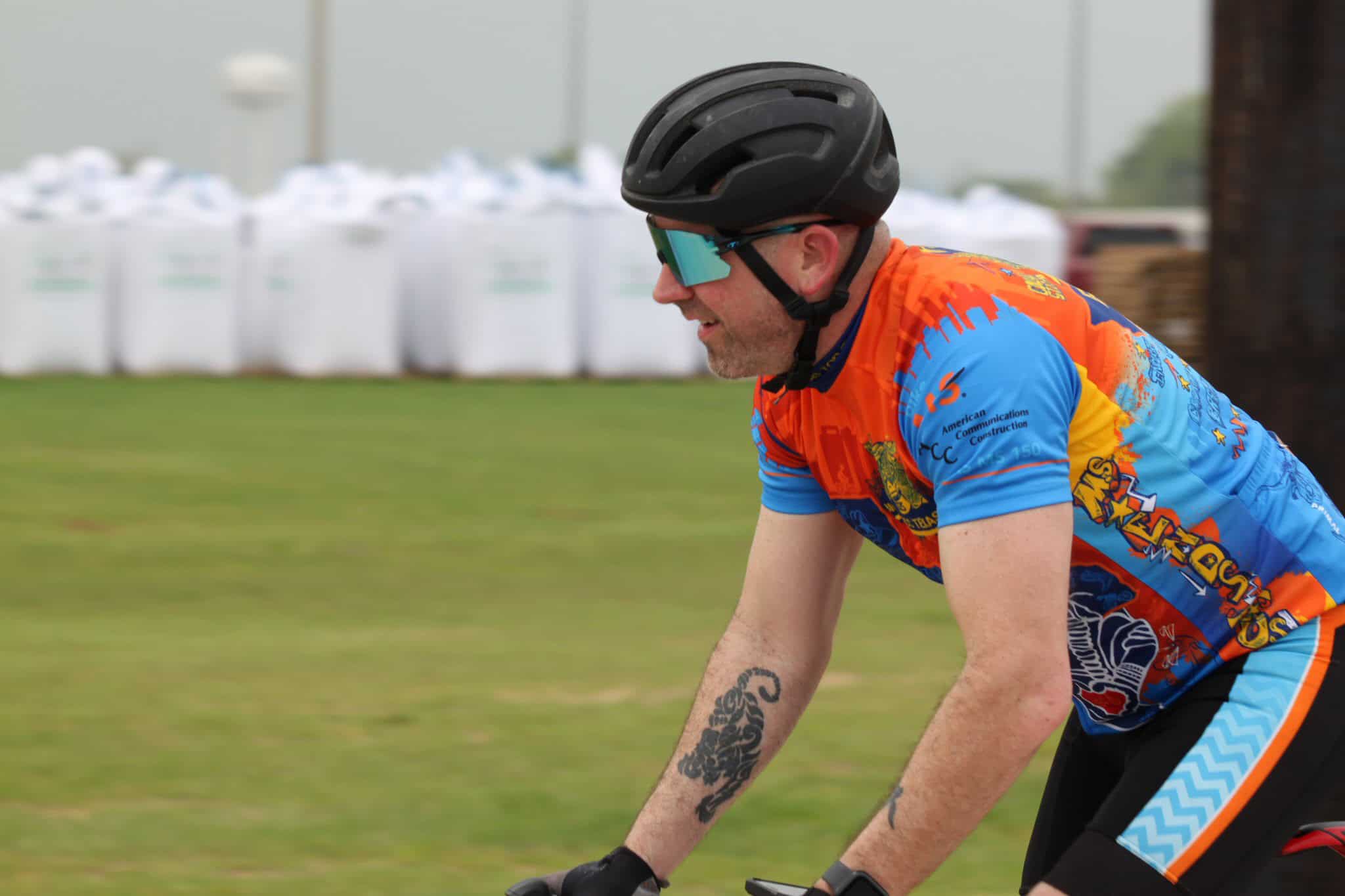 Bright cyclist wearing colorful jersey and helmet riding a bike outdoors for Bluebonnet Express.