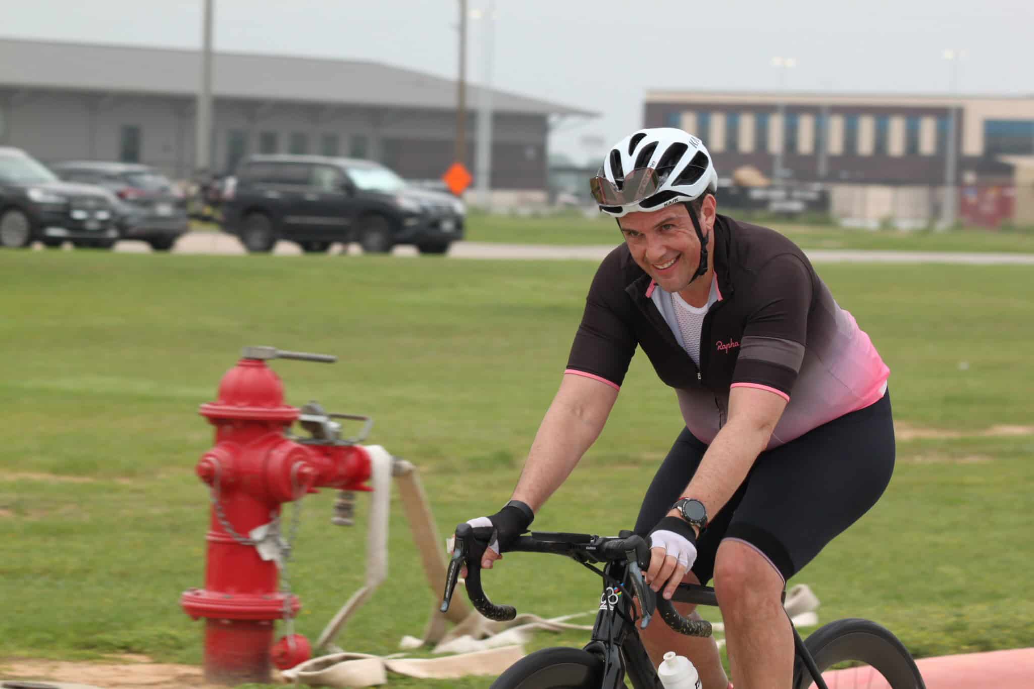 Bright smiling cyclist riding on green grassy field during daytime.