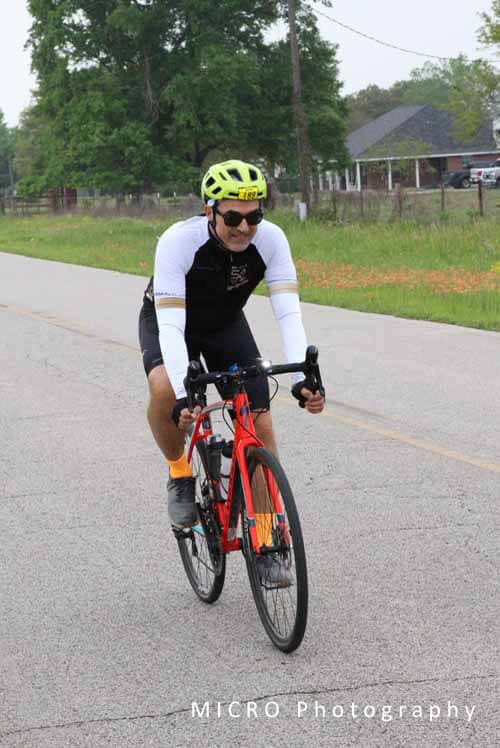 Vibrant cyclist riding on open road in bright helmet and athletic gear for fitness and outdoor cycling.