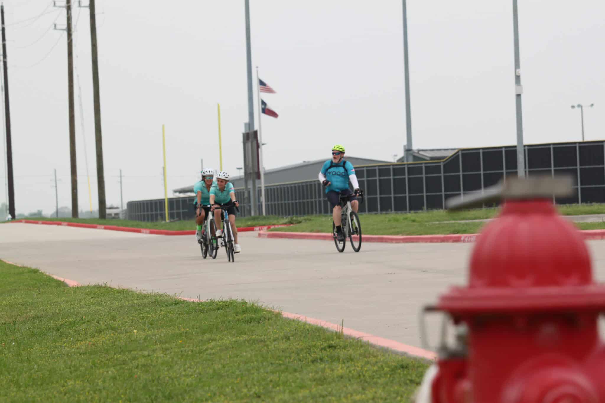 Bicycle riders enjoying a group ride along a paved trail on a cloudy day.