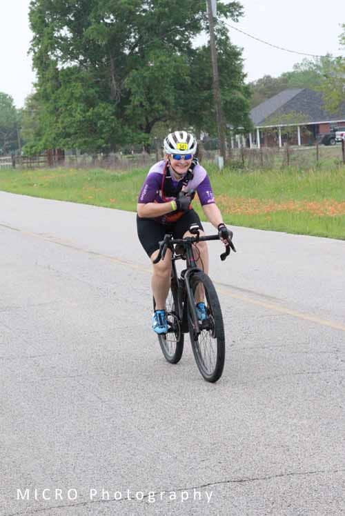1. Smiling cyclist riding on rural road during Bluebonnet Express event.