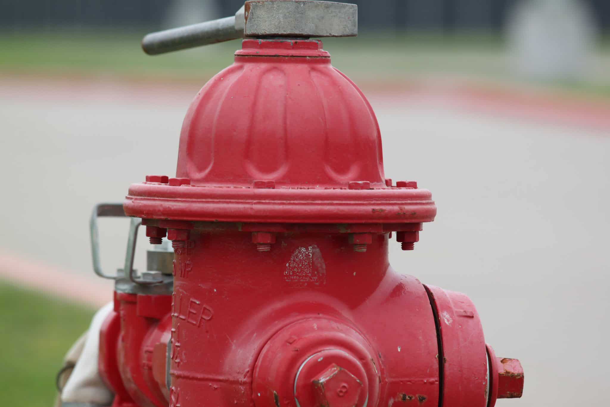 Red fire hydrant on a city street, safety feature for fire emergencies.