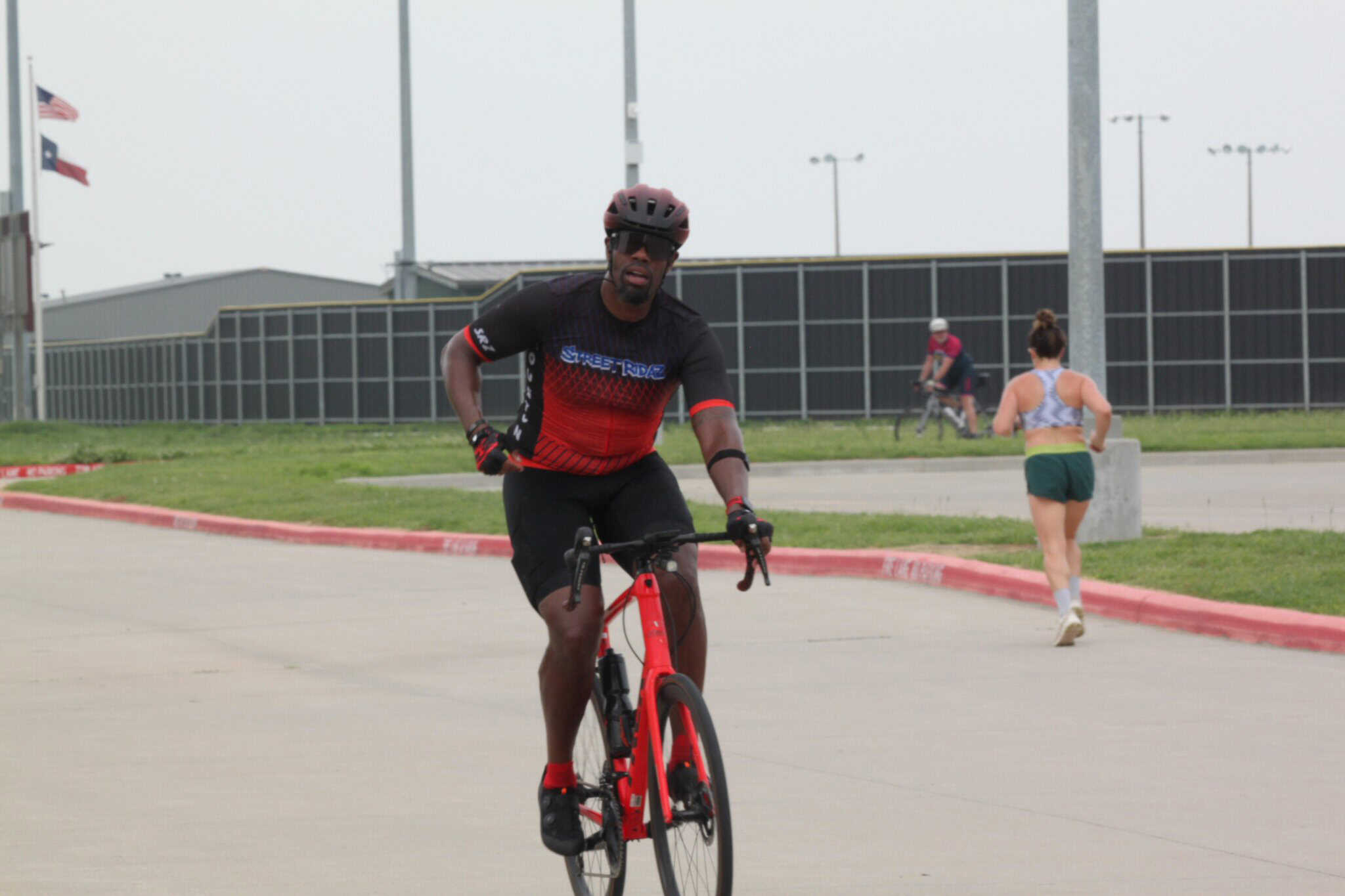 Vibrant cyclist riding a red bike at Bluebonnet Express event, outdoor urban setting, fitness, active lifestyle.