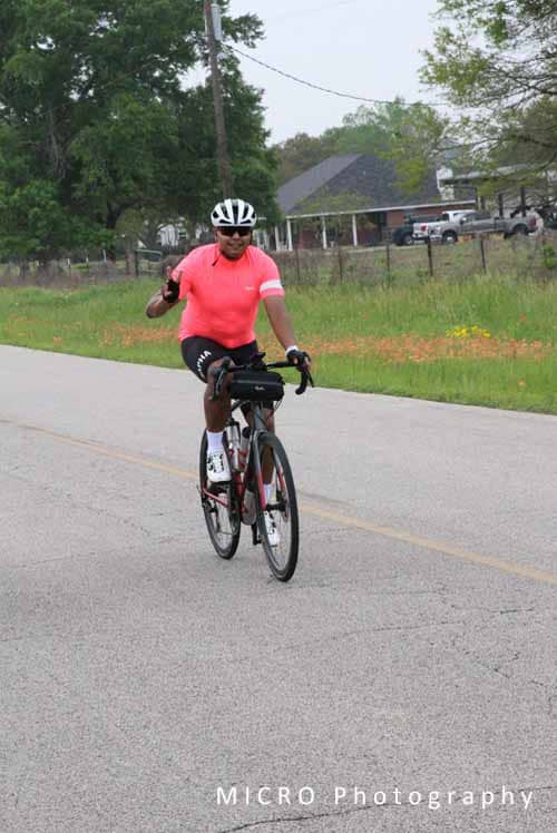 Bright pink cycling jersey on woman riding bicycle on scenic rural road during daytime.