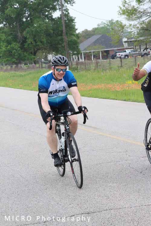 Cyclist in blue Wilkins jersey riding on road during Bluebonnet Express race.