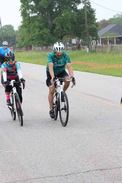Riders participating in Bluebonnet Express cycling event on a scenic rural road during daytime.