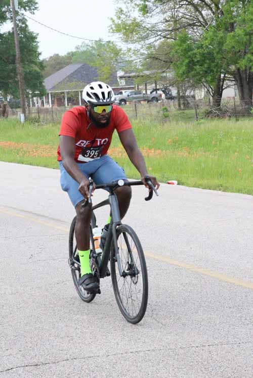 Fast cyclist in red jersey riding on the road during the Bluebonnet Express event.