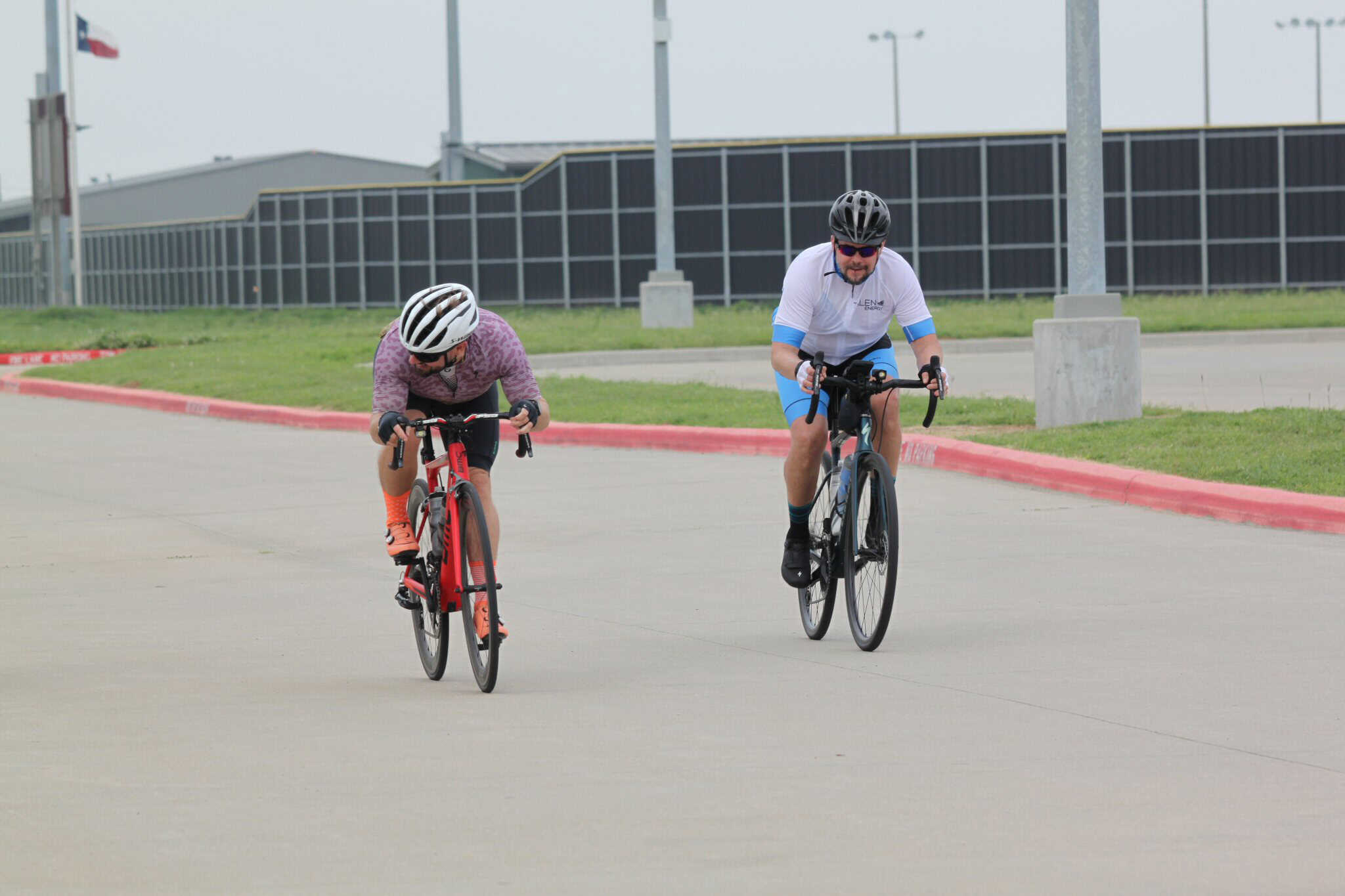 Cyclists riding on a paved road with green surroundings, promoting active transportation and eco-friendly travel.