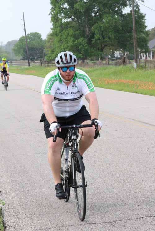 Riding cyclist in Wellboro Integrate jersey on a scenic open road during Bluebonnet Express event.