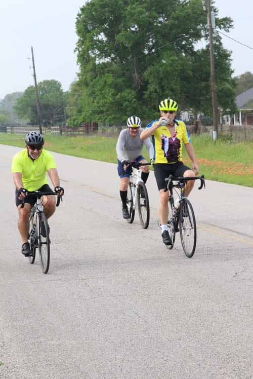 Bright cyclists on Yellowbonnet Express bikes riding on scenic rural road in Texas.