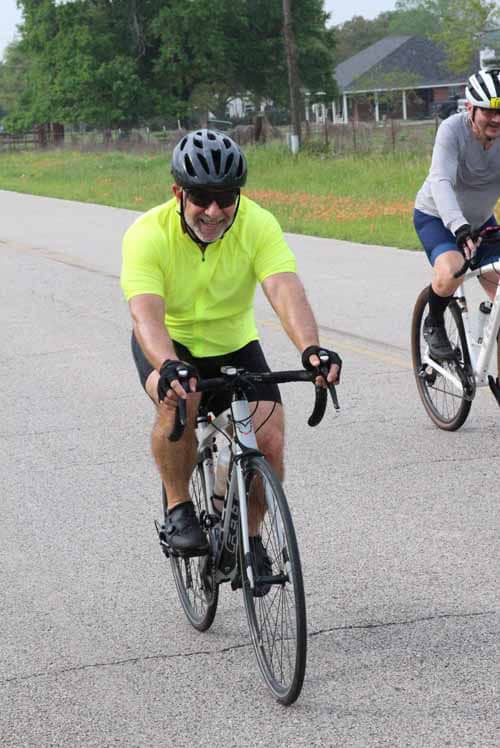 Bright yellow cycling jersey, smiling cyclist, Bluebonnet Express triathlon, outdoor bike race, active lifestyle, fitness event.