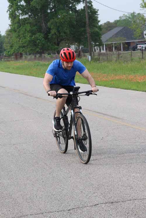 Vibrant cyclist riding on a suburban road during daytime, enjoying outdoor biking adventure.