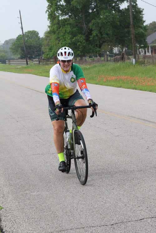 Colorful cyclist riding on rural road during Bluebonnet Express event.