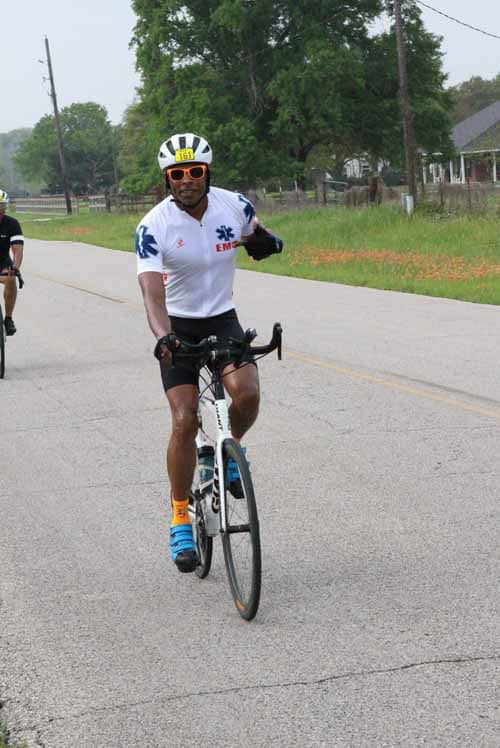 Brightly dressed cyclist riding along scenic rural road for Bluebonnet Express event.