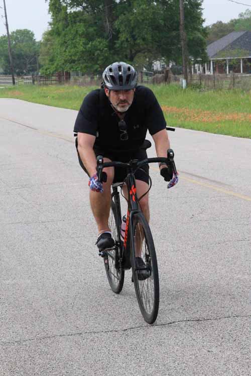 Sharp-eyed cyclist riding on rural road with lush greenery, highlighting outdoor biking adventure.