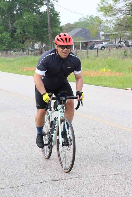Balanced cyclist wearing a red helmet on a peaceful rural road, promoting outdoor biking and fitness.