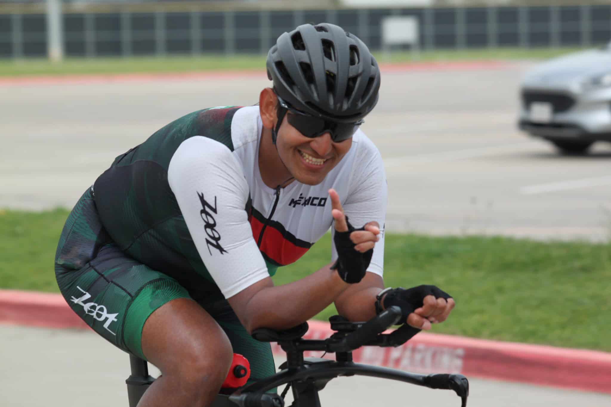 Happy cyclist in helmet and sunglasses giving a thumbs-up during training ride.