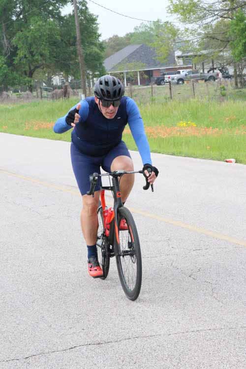 - Man riding a bike on a country road, wearing a helmet and athletic gear.