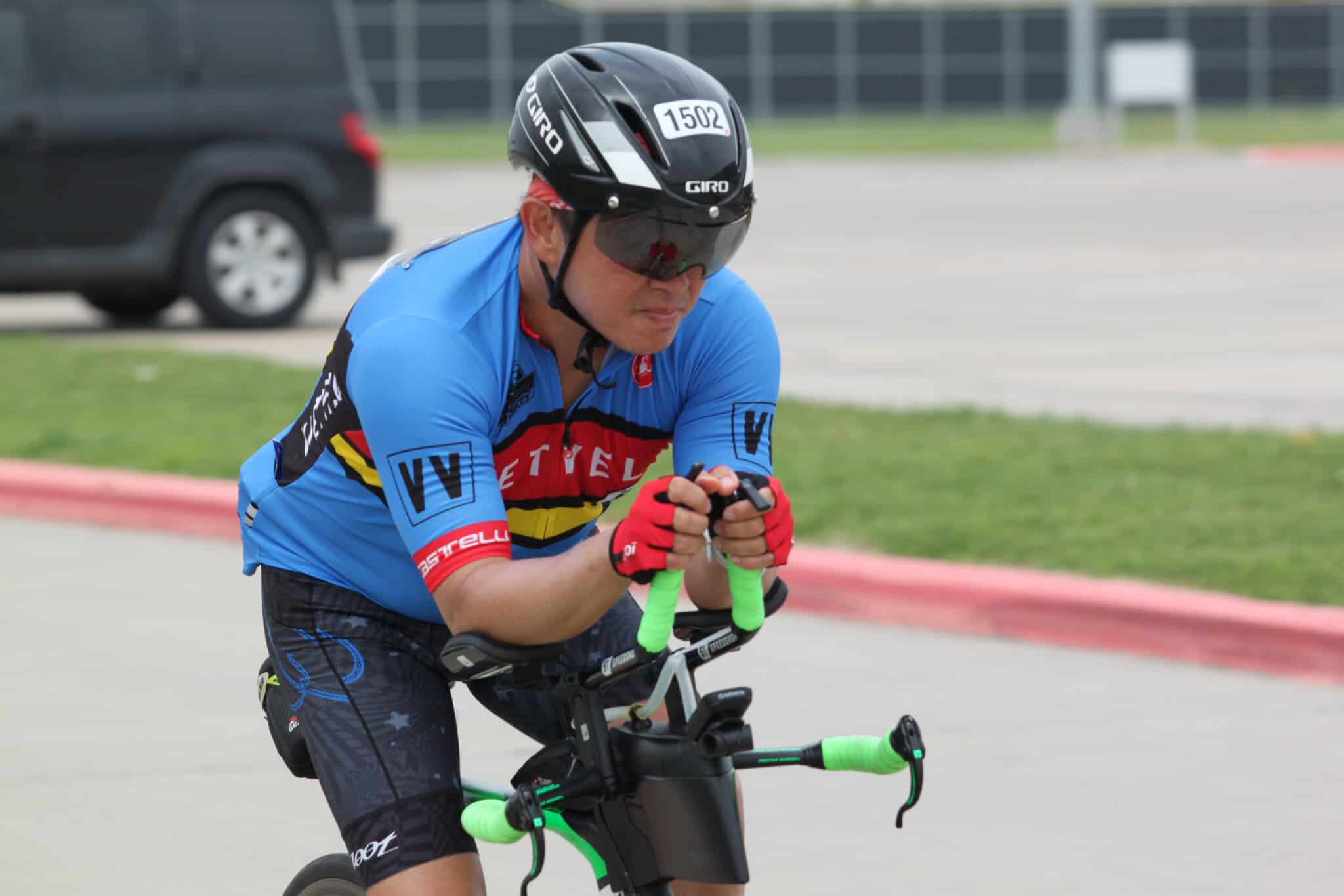 High-performance cyclist wearing a blue team jersey and helmet, using an electric bike at the Bluebonnet Express event.