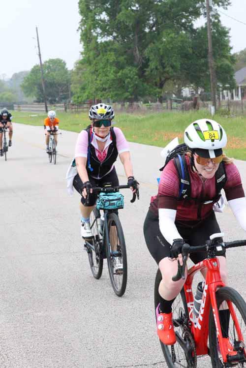 Bright female cyclists riding on rural road during outdoor group bike ride.