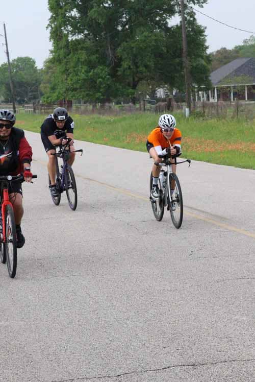 Bright young cyclists riding on a scenic rural road, participating in Bluebonnet Express bike event.