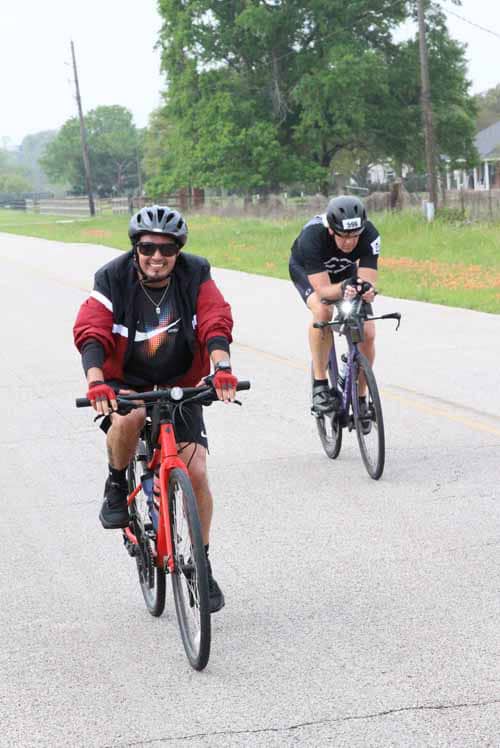 Sunny cyclists riding on a scenic rural road during daytime.